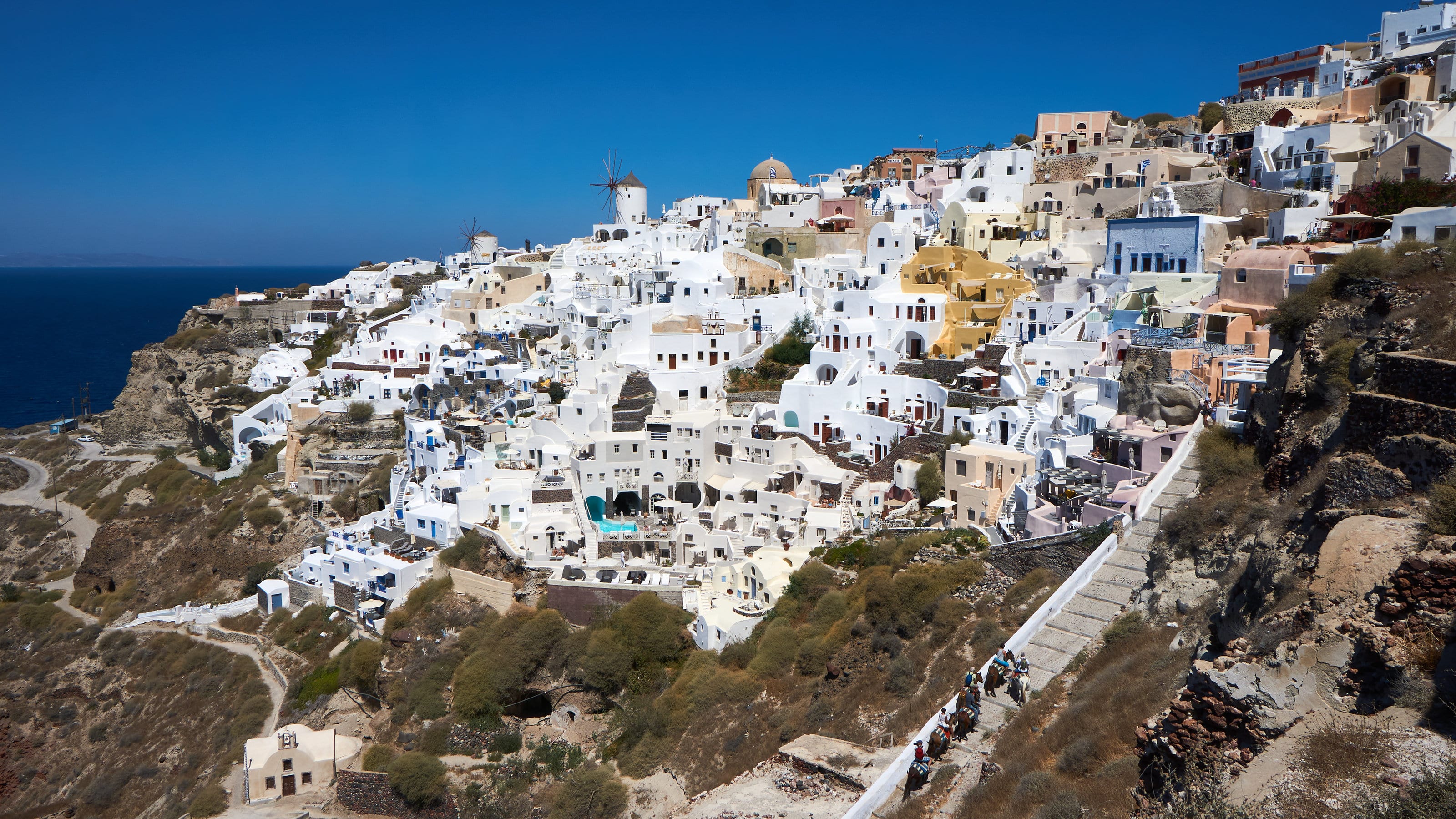 Casas brancas e um moinho de vento sobre o penhasco da caldeira, em Oia, na ilha de Santorini.