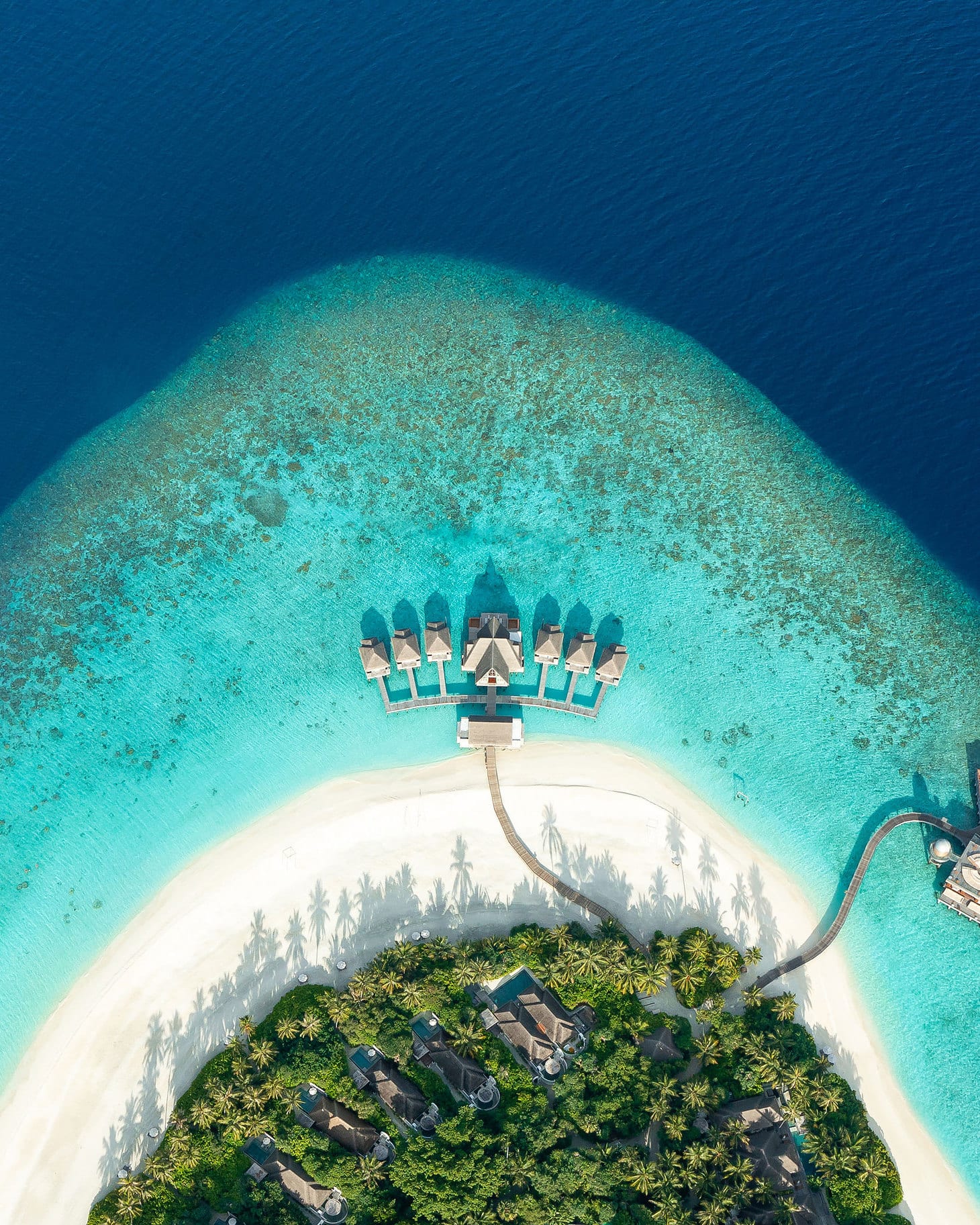 Vista aérea de uma ilha cercada por recifes de água turquesa nas Maldivas.