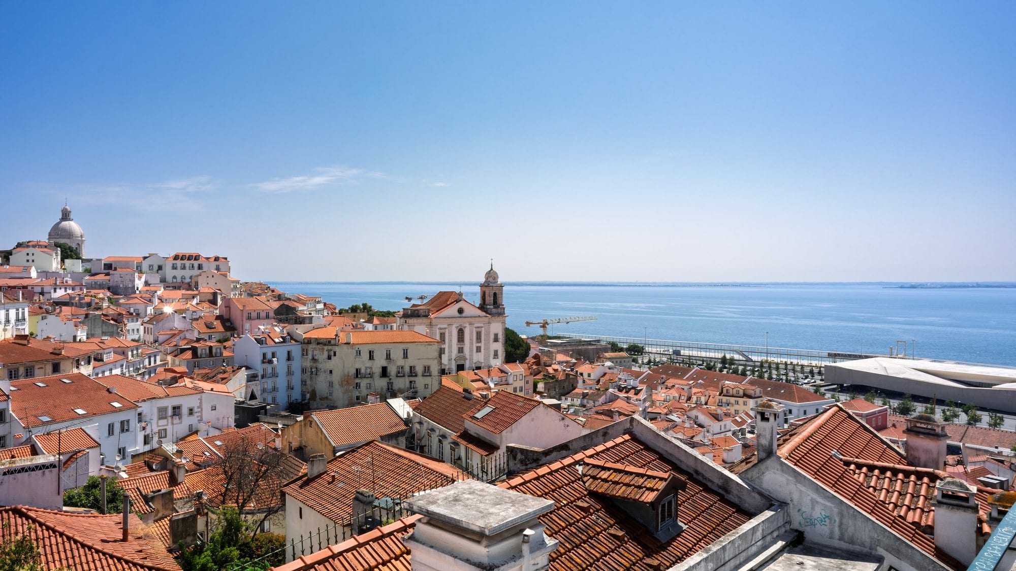 Telhados alaranjados do bairro de Alfama e o rio Tejo ao fundo, em Lisboa.
