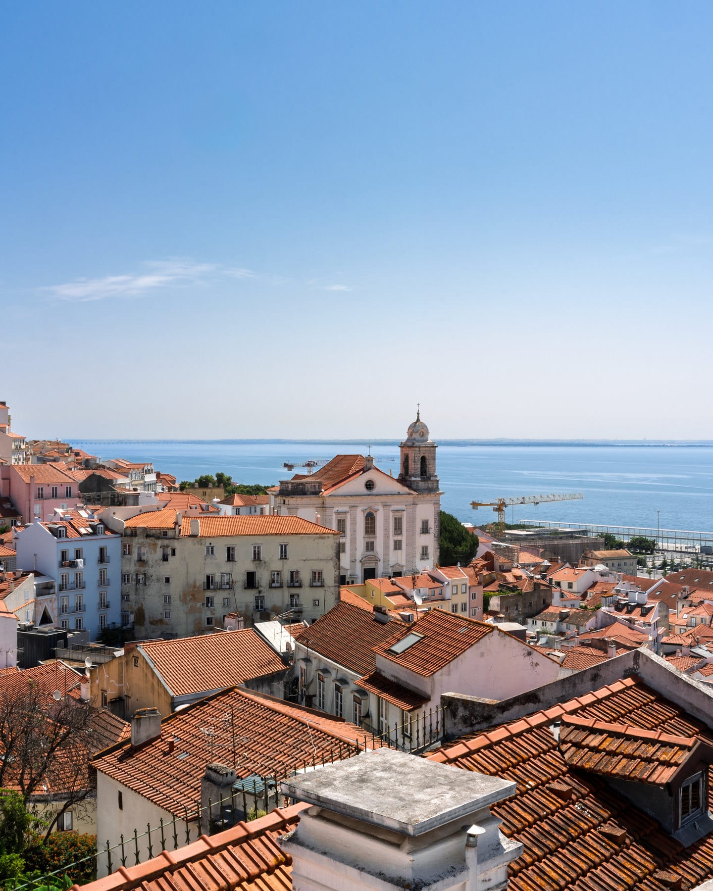 Telhados alaranjados do bairro de Alfama e o rio Tejo ao fundo, em Lisboa.
